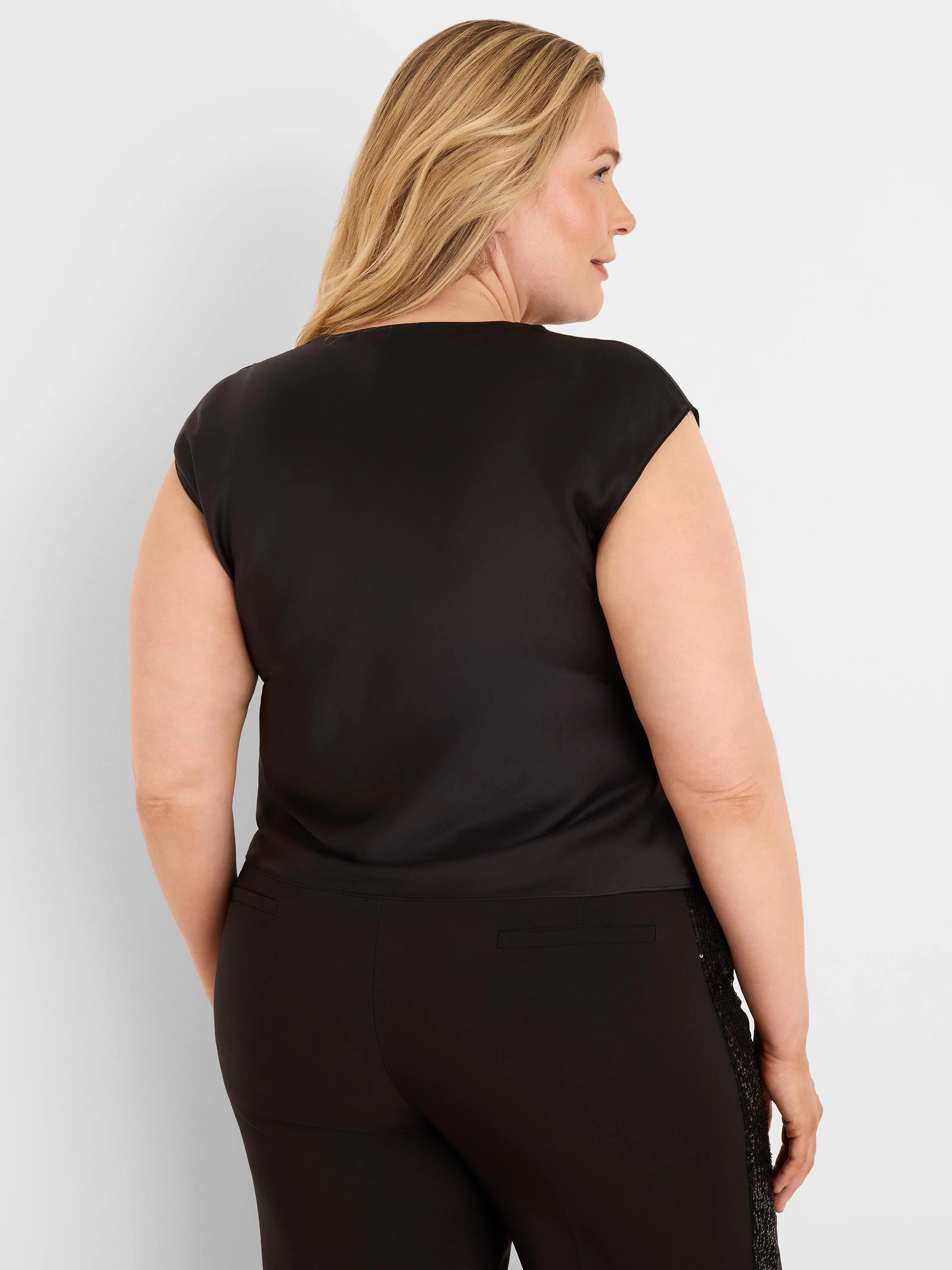 Black glossy tee with short cap sleeves, worn by a model facing away.