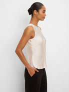 Sleeveless, round-neck tank in shimmering light champagne, worn by model.