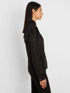 Black chiffon shirt with metallic gold vertical dashes, ruffled high collar and shoulder details.