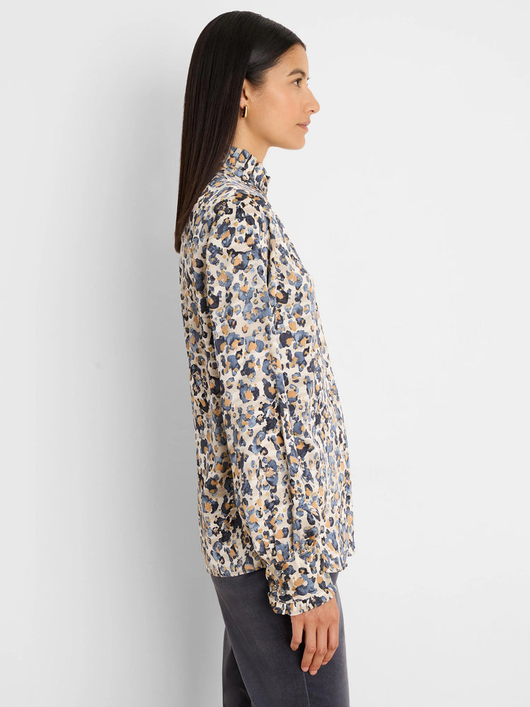 Loose-fit cream shirt with abstract blue, gold, and dark grey spots, ruffled high neck and cuffs.