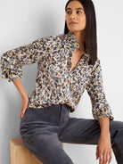 Cream shirt with an abstract pattern of dark blue, grey-blue, and gold flakes. Features a ruffled collar and gathered cuffs.