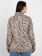 Back of a shirt with cream base, blue-gray, black, and gilded tan abstract spots. Features ruffled collar and cuffs.