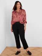 Red, pink, and orange abstract striped shirt with fine vertical pleats, collared and long sleeves rolled up.
