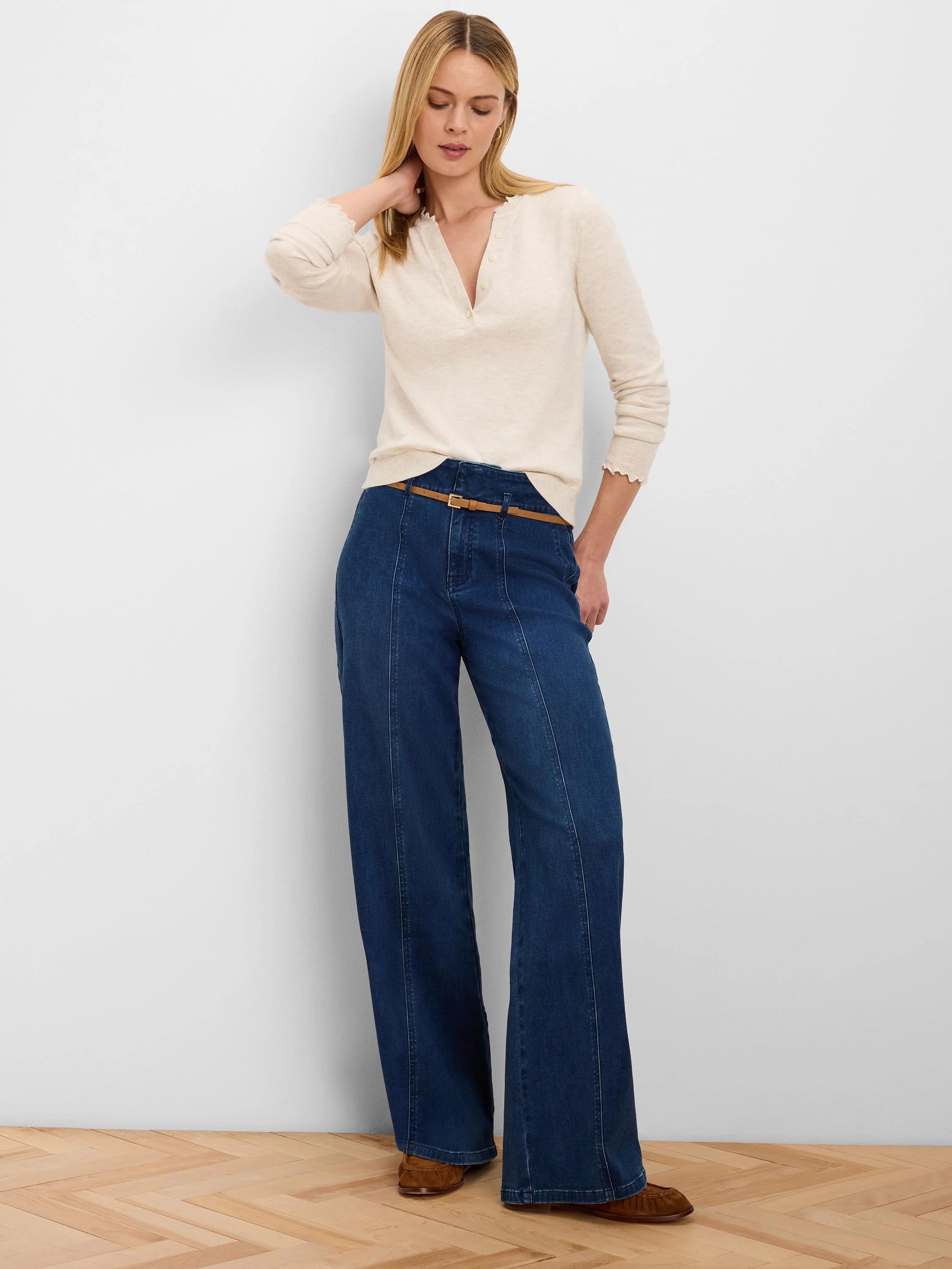 Dark blue wide-leg belted jeans with vertical front seams and a thin tan belt.