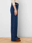 Dark blue wide leg jeans, side view. Features a thin tan belt at the high waist.