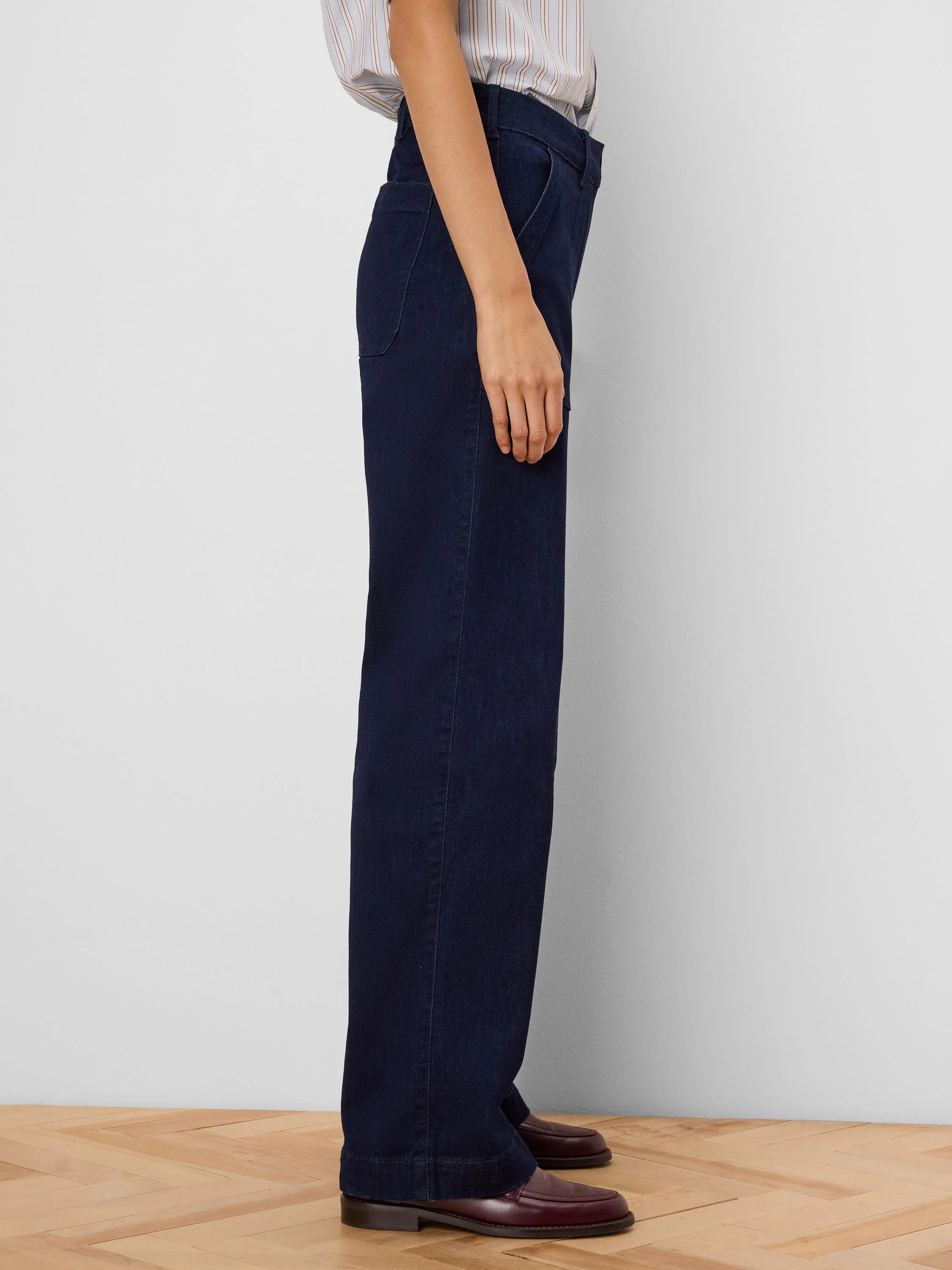 Dark indigo wide-leg jeans with a visible folded cuff, viewed from the side on a model.