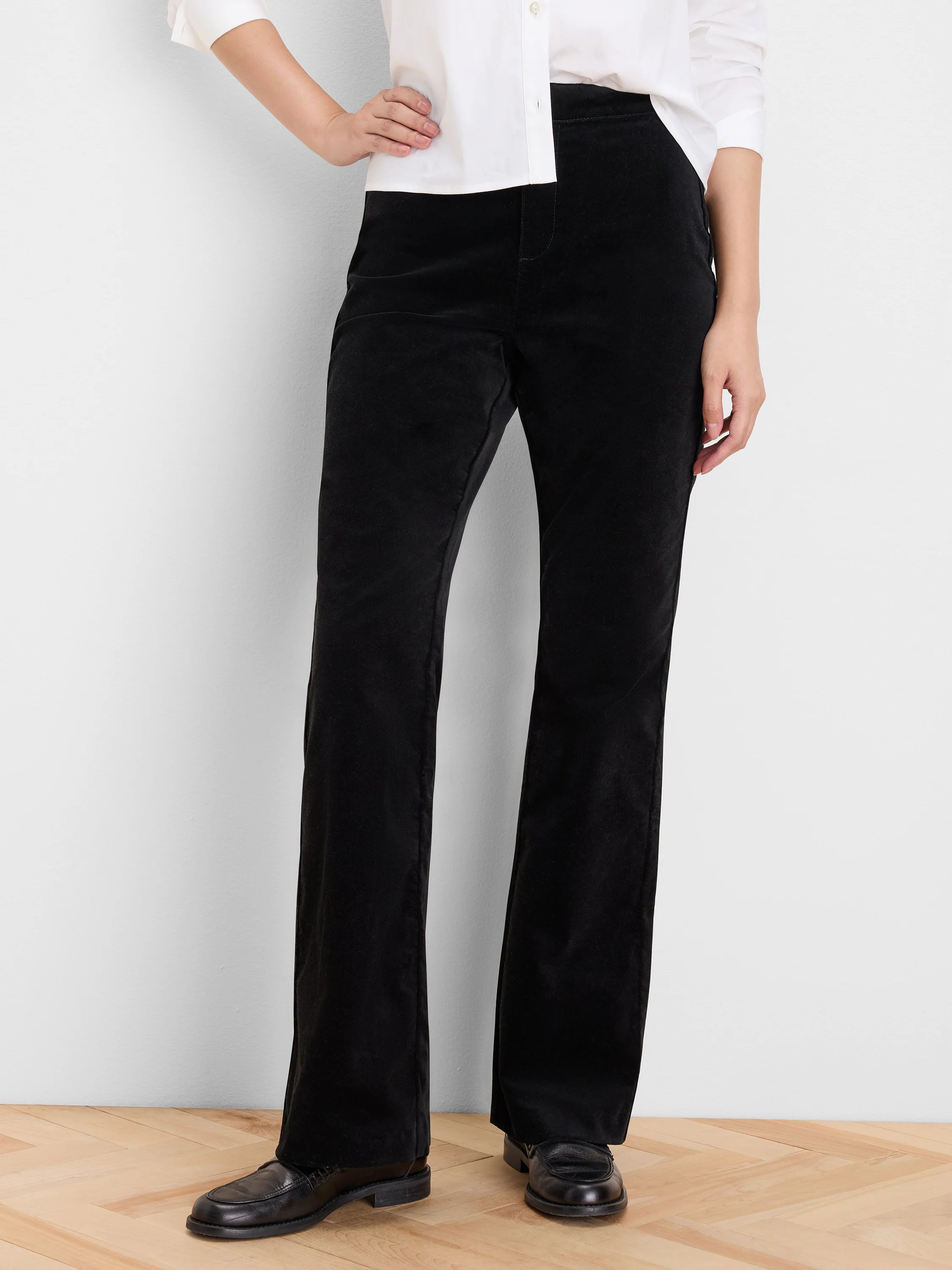 Black high-rise stretch velvet pants with a boot-cut leg, shown on a model.