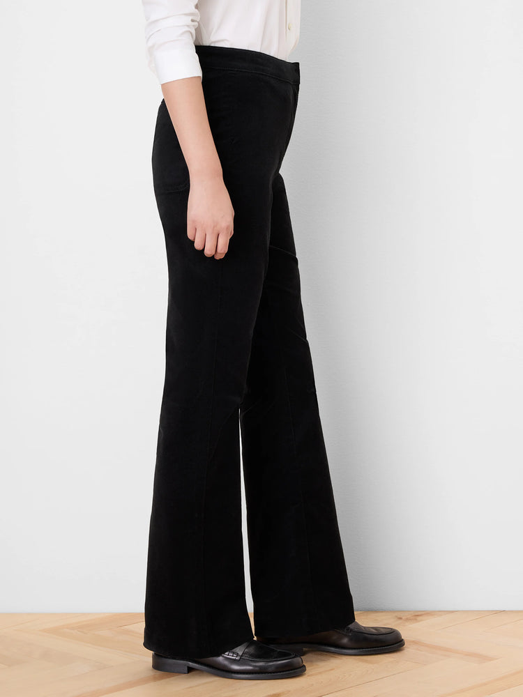 Black velvet high-rise boot-cut pants, side view. Legs flare widely from the knee, covering the feet.
