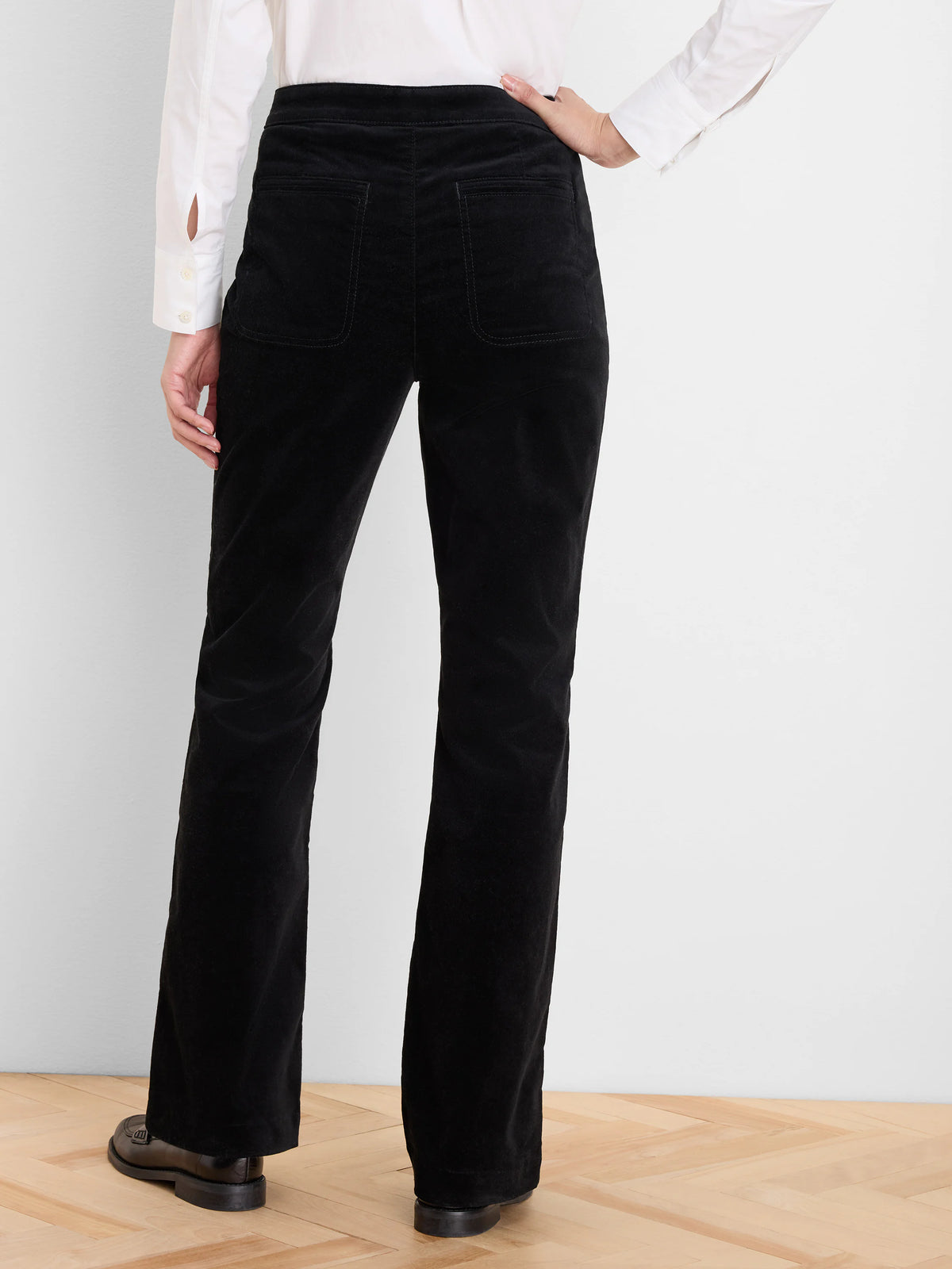 Black stretch velvet high-rise bootcut pants, shown from the back with two visible back pockets.