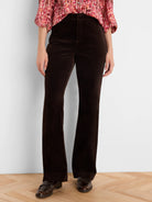 Dark brown high-rise velvet bootcut pants on a person.