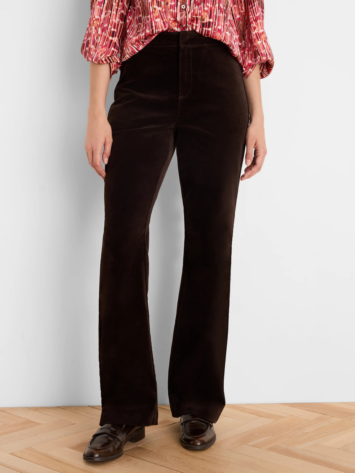 Dark brown high-rise velvet bootcut pants on a person.