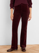 Burgundy high-rise velvet boot-cut pants on a person, paired with a matching sweater and dark brown loafers.