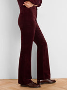 Dark red high-rise stretch velvet pants. Fabric has a soft texture, subtle sheen, and bootcut flare.