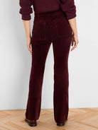 Rear view of burgundy velvet high-rise boot-cut pants with two back patch pockets.