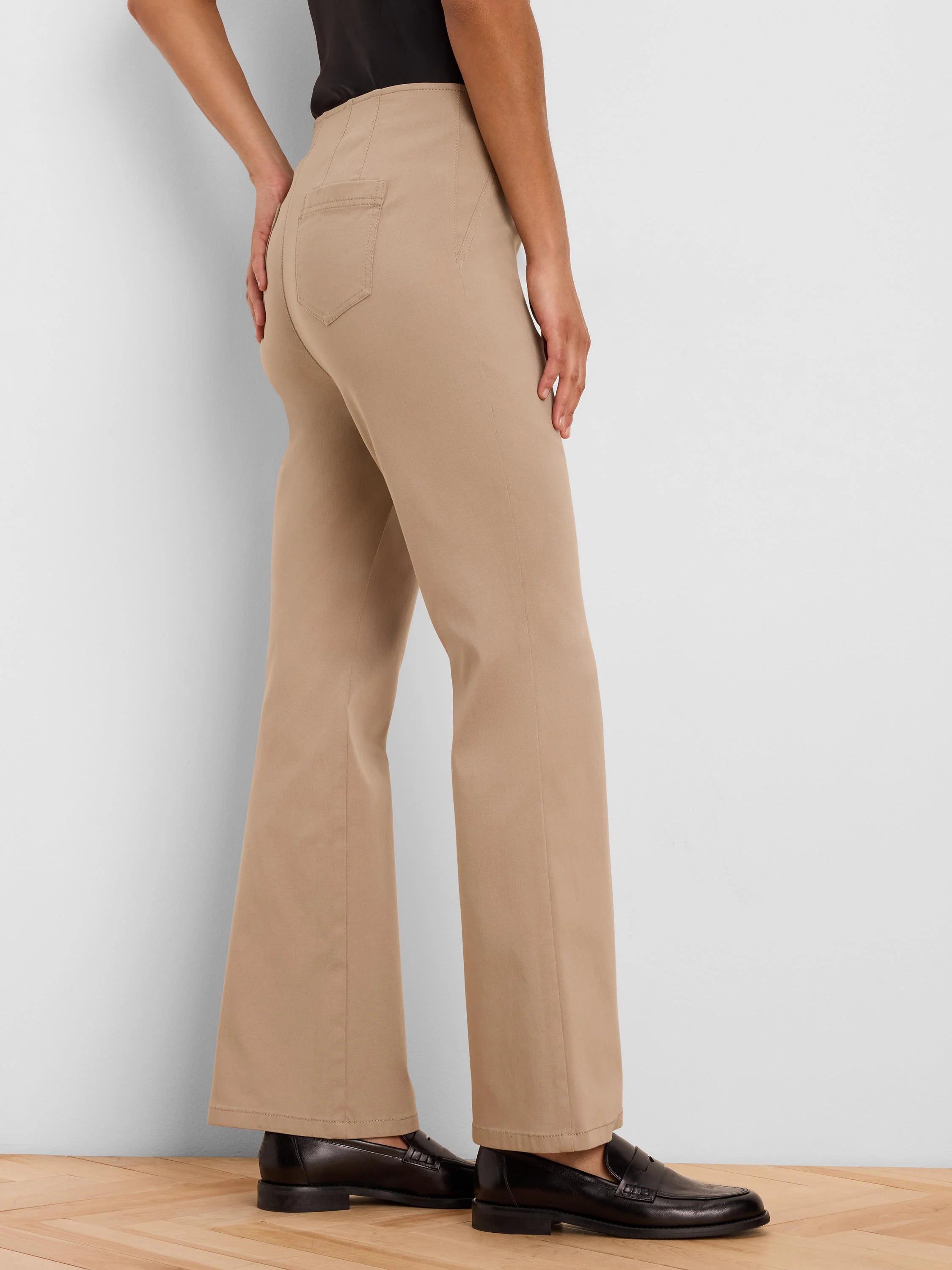 Tan high-waisted bootcut pants with back pockets, shown from behind on a model.