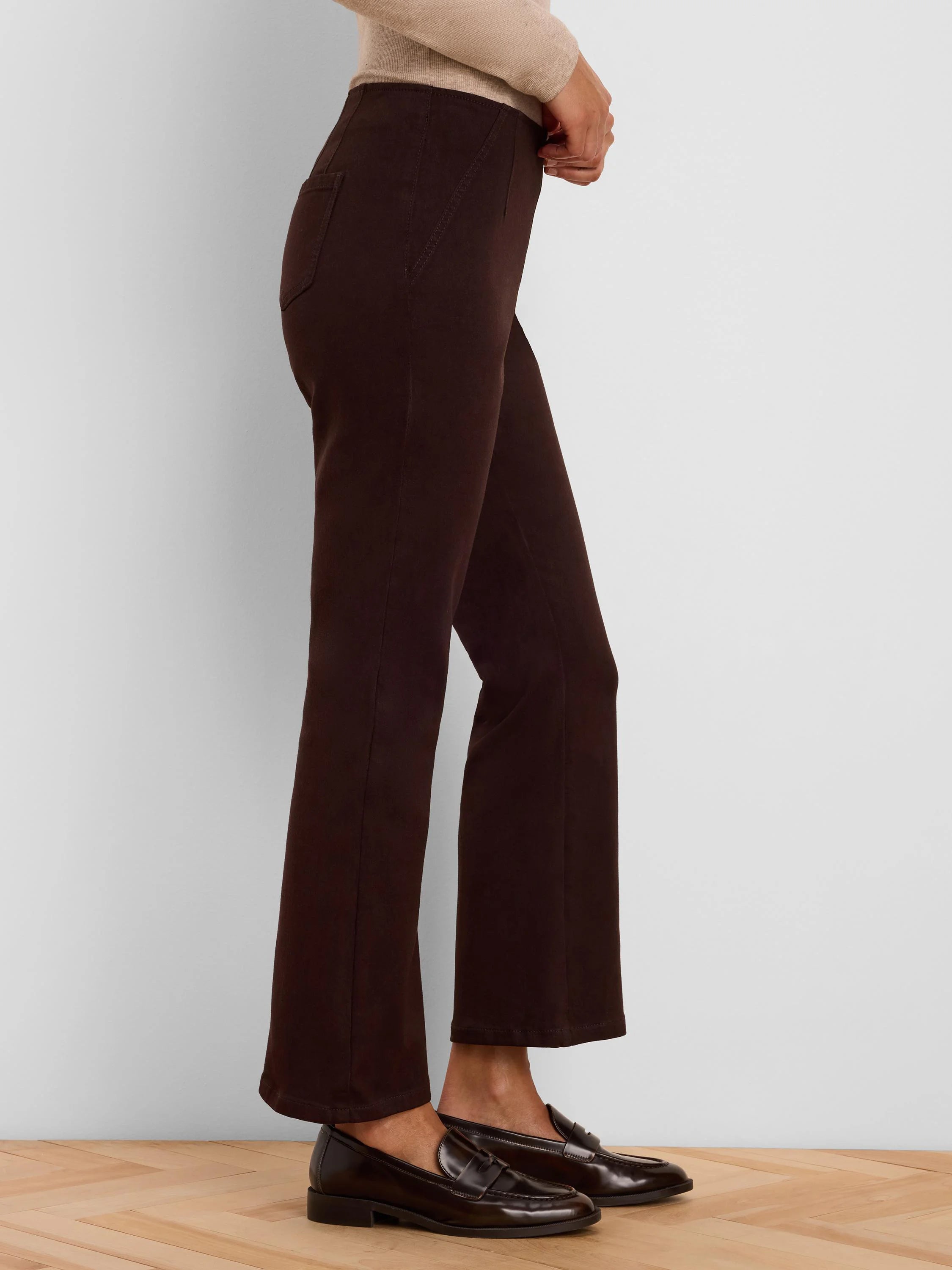 Dark brown bootcut jeans, high-waisted with V-stitching on the front.