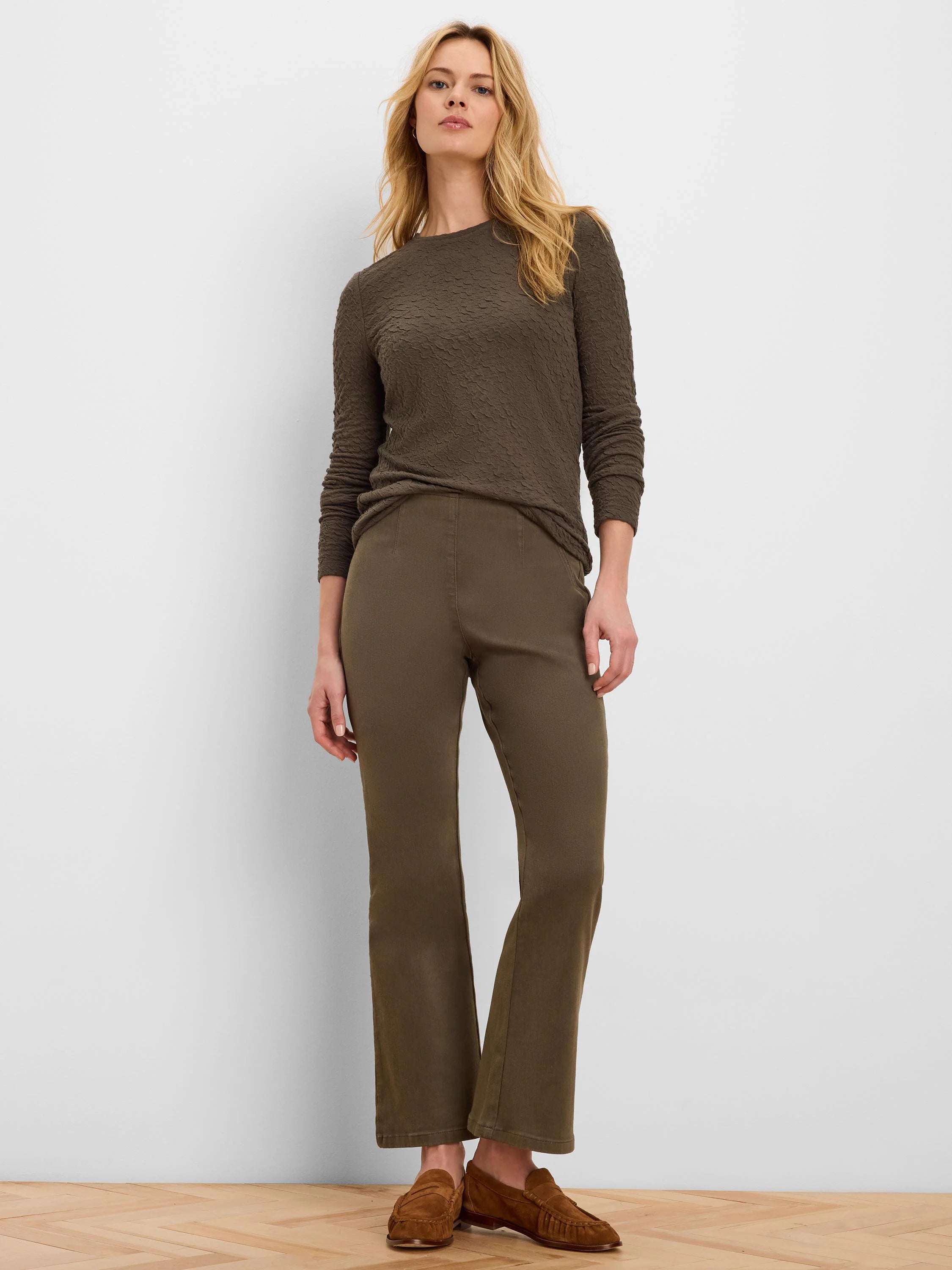 Olive green bootcut jeans, fitted through the thigh with a subtle flare, featuring a smooth, flat waistband.