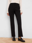Black high-rise, straight-leg pants with a smooth finish, worn by a model with a light top and black loafers.