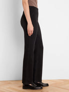 Black bootcut jeans, modeled from the side. They have a slight flare below the knee and subtle vertical seams.