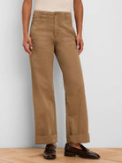 Tan wide-leg pants feature a high waist, angled front pockets, and cuffed hems.