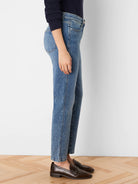 Medium blue, faded straight-leg jeans modeled on a person, showing an ankle-length fit.