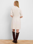 Pale beige knee-length dress, back view. Features elbow sleeves, belted waist, and brown contrast topstitching.