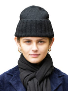 Charcoal hand-knit flat hat with a wide ribbed cuff, worn on a model's head.