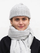 Light grey, hand-knit flat hat with a ribbed texture.