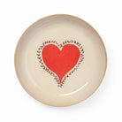 Cream ceramic dish with a red heart graphic centered within a dark vine pattern and accented by a golden yellow rim.