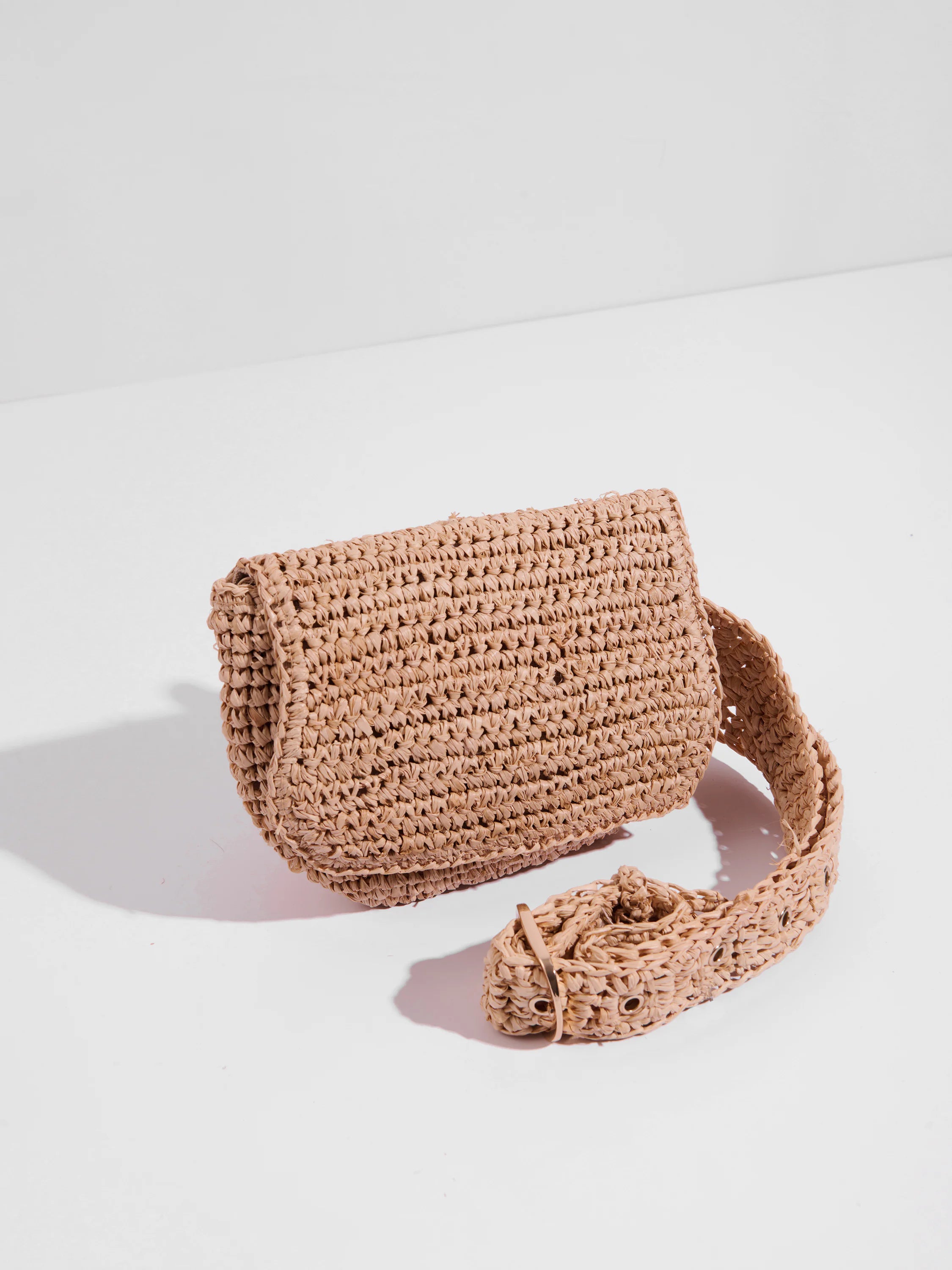 Light beige straw belt bag.  Crocheted texture.  Bag is curved;  long strap with small metal buckle.