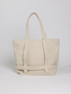 Off-white canvas tote bag with two top handles and a reinforced bottom.  The bag features a woven detail across the bottom.