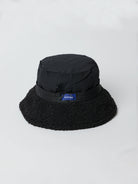 Black quilted bucket hat with a black fuzzy brim.  Small navy blue logo tag.