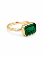 Gold ring with a rectangular green stone, bezel-set.