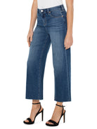 Mid-rise, wide-leg jeans; medium-wash blue denim with frayed hems.  Model wears black heels.