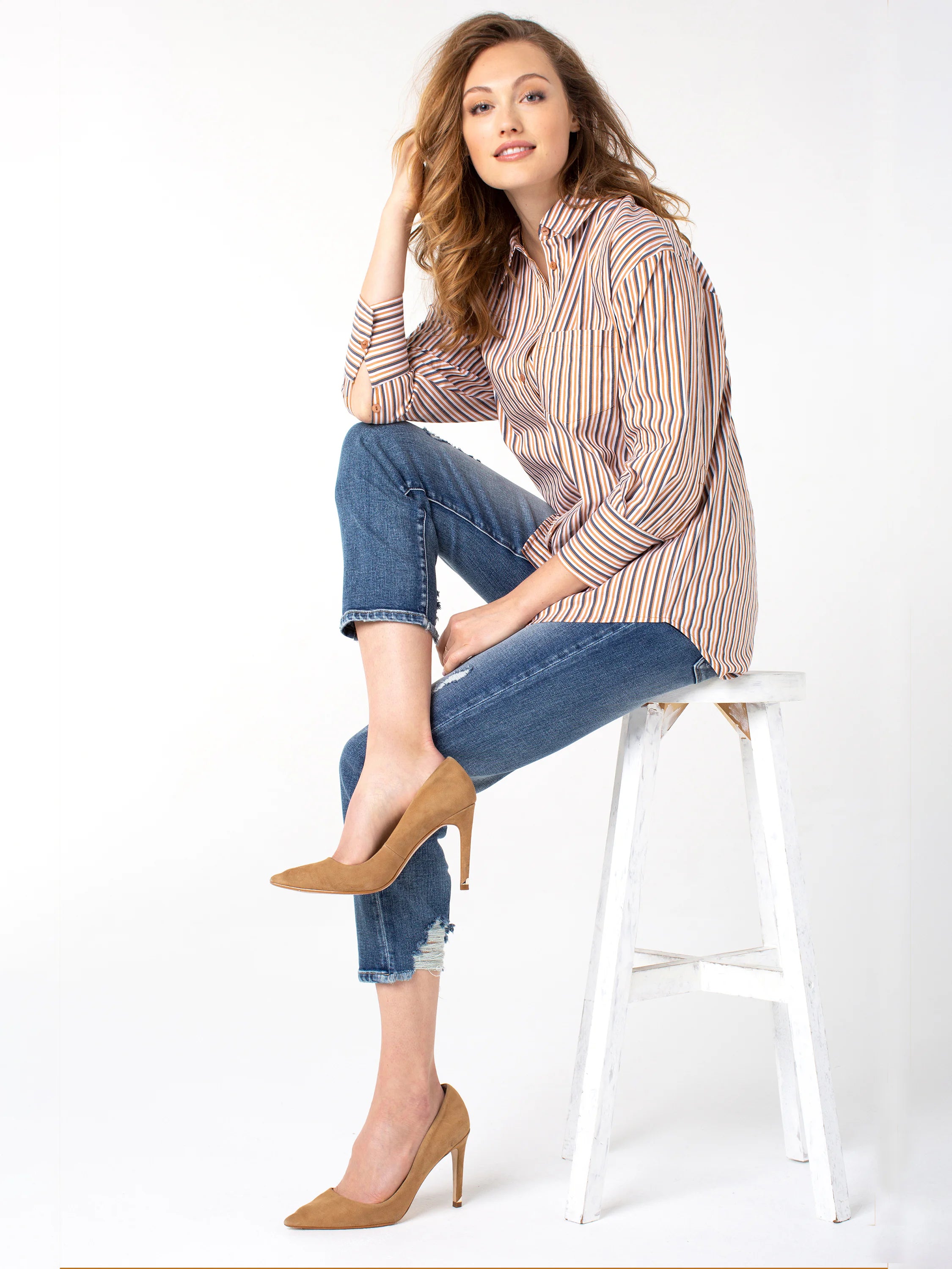 Straight, cropped blue jeans with distressed hems.  Model wears tan heels and a vertically striped shirt in beige, navy,...