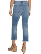 Light wash blue cropped jeans, frayed hem.  Back view. Model wears tan wedges.