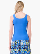Model's back in a bright blue fitted tank with wide straps and a scoop back.