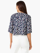 Dark indigo cardigan with white geometric angles, accented by pink and orange shapes. Model from back.