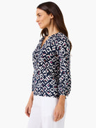 Indigo V-neck top with white geometric angled pattern, accented by pink & orange shapes. 3/4 gathered sleeves.