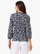 Navy geometric pattern top with white, pink, and orange accents. Features a ruffled stand collar and 3/4 elastic cuff...