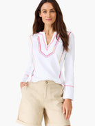 White V-neck long-sleeve top with geometric pink, orange, and dark red embroidery on the neckline and sleeves.