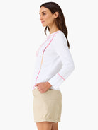 White long-sleeved top with vertical pink, orange, and beige embroidery on the front and sleeve cuffs.
