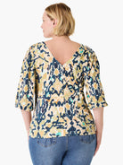 Back view of a multi-color top with dark blue, olive, mustard, beige, teal abstract pattern. Features a V-neck back and...