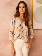 Beige V-neck sweater with blue-gray and white abstract pattern. Long sleeves.
