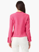 Back of hot pink knit jacket with fringe at collar, cuffs, and hem.