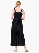 Black Kara dress featuring a ribbed tank top bodice and a pleated midi skirt. View from the back.