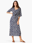 Midi indigo dress with white geometric pattern, pink/orange accents, tie waist, and elbow sleeves.