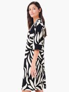 Black V-neck dress with off-white and yellow abstract leaf print. Relaxed fit, elbow sleeves, knee-length.
