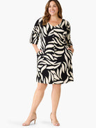 Black V-neck dress with cream abstract leaf print, 3/4 sleeves, knee-length, and side pockets.