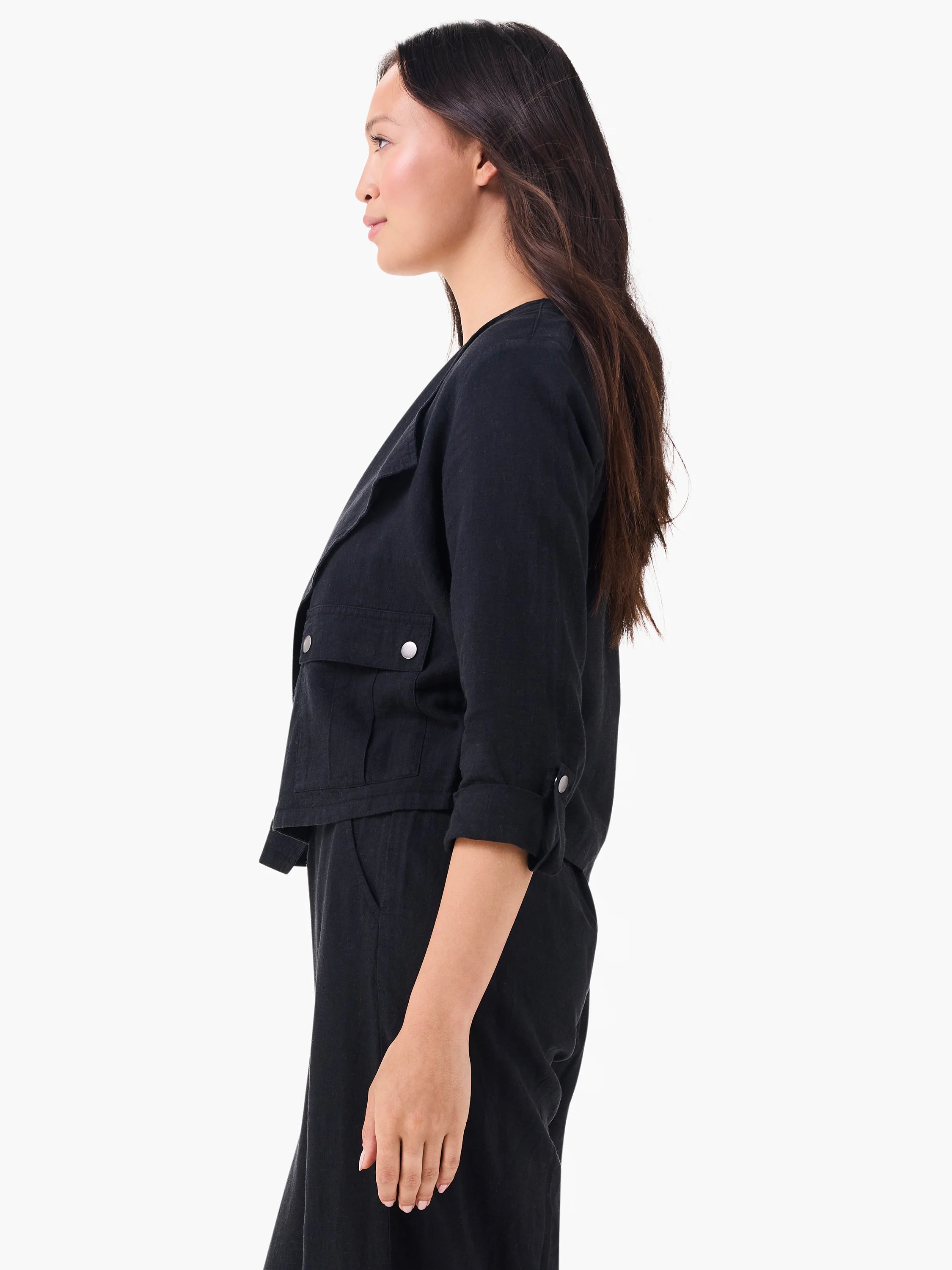 Black linen moto jacket with wide lapels, two flap chest pockets, and rolled 3/4 sleeves with silver buttons.